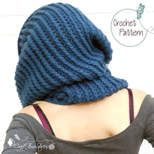 May include: A blue crocheted cowl or hood with a ribbed texture. The cowl is worn by a person with a gray shirt. The text "Crochet Pattern" is visible in the image.