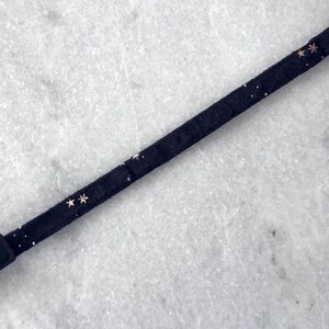 Puede incluir: Un collar negro ajustable con detalles de estrellas doradas. El collar est&aacute; hecho de una tela suave y c&oacute;moda.