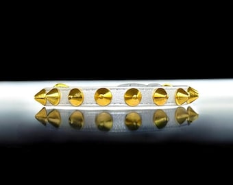 Könnte beinhalten: Weißes Lederhalsband mit goldenen pyramidenförmigen Nieten.