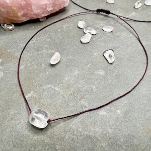Peut inclure: Un pendentif en cristal de quartz clair sur un collier en cordon rouge foncé. Le pendentif est de forme irrégulière naturelle et mesure environ 2,5 cm de long.