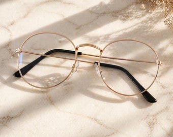 Gafas ovaladas de estilo vintage en oro rosa con luz azul y montura fina de metal.