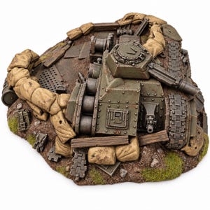 Könnte beinhalten: Ein olivgrünes Panzermodell in einem befestigten Schützengraben-Diorama. Die Szene zeigt beigefarbene Sandsäcke, verwitterte Holzplanken und metallische Kettensegmente auf einem strukturierten Untergrund mit grünen Grasflecken.