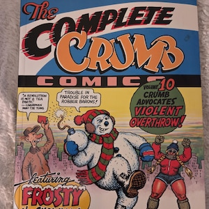 Op de afbeelding: The Complete Crumb Comic Volume 10 met Frosty the Snowman. De cover toont een cartoon sneeuwman met een bom, een man met een hoed en een vrouw in een rode jas. De strip heeft de tekst "Violent Overthrow!"