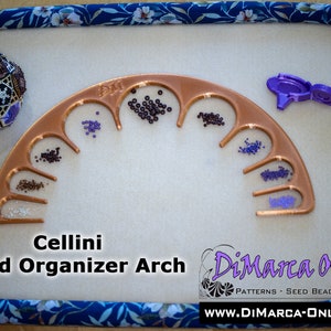 Könnte beinhalten: Ein kupferfarbener Perlen-Organizer-Bogen mit 10 Fächern, die jeweils mit verschiedenen farbigen Perlen gefüllt sind. Der Bogen ist mit "Cellini Bead Organizer Arch" beschriftet und befindet sich auf einer weißen Oberfläche. Der Text "DiMarca Online" ist in der unteren rechten Ecke des Bildes sichtbar.