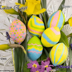 以下が含まれることがあります： ピンク、黄色、青、緑など、さまざまな色のビーズで作られたイースターエッグのコレクション。卵は幾何学模様で装飾され、黄色の水仙と紫の花と一緒に展示されています。「Easter Eggs」と「Peyote Egg」の文字が見えます。