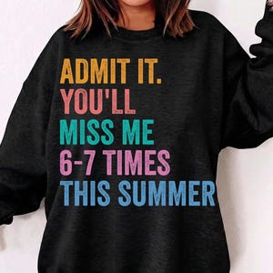 Könnte beinhalten: Schwarzes Sweatshirt mit dem Text "ADMIT IT. YOU'LL MISS ME 6-7 TIMES THIS SUMMER" in Orange, Rosa, Grün und Blau. Das Sweatshirt hat einen lässigen Stil.