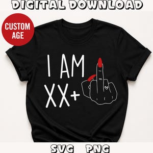 Op de afbeelding: Zwart T-shirt met de witte tekst "I AM XX+". Een hand met een rode nagel geeft de middelvinger, met een klein hartje. De woorden "DIGITAL DOWNLOAD" en "SVG PNG" zijn ook zichtbaar.