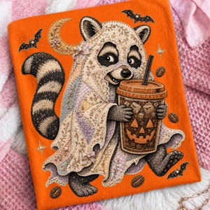 May include: A bright orange fabric featuring a raccoon wearing a floral patterned ghost costume. The raccoon holds a brown coffee cup with a jack-o'-lantern face. The design includes small black bats, coffee beans, and star accents scattered across the orange background.