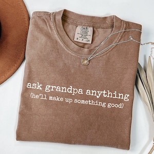 May include: A white ceramic mug with a black handle and the text "But First, Coffee" in a black, bold font. The mug is sitting on a wooden surface. The mug is 4 inches tall.