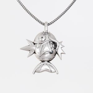 May include: A silver pendant necklace with a fish-shaped charm. The pendant has a rounded body, spiky fins, and a detailed face. The chain is a fine, textured silver. The necklace is suitable for everyday wear.
