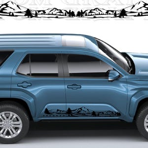 以下が含まれることがあります： 青いSUV。側面には黒い山と木のデカールが付いています。デカールは車両の上にもあります。「4RUNNER」の文字がデカールに表示されています。車両にはシルバーのリムとサンルーフが付いています。