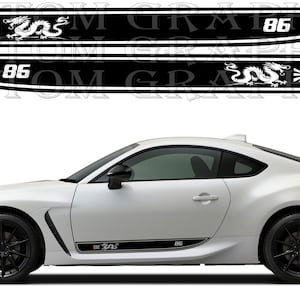 Può includere: Auto sportiva bianca con cerchi neri e decalcomanie laterali. Le decalcomanie sono nere con grafiche di drago bianco e sole nascente, e il numero "86". L'auto ha un design elegante e moderno.