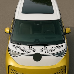Puede incluir: Vista aérea de un vehículo eléctrico amarillo y blanco con techo corredizo negro. El capó presenta un diseño floral negro. Hay un círculo negro en el capó.