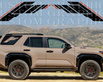 Può includere: Un SUV beige con dettagli neri e pneumatici fuoristrada è mostrato di profilo. Sopra il veicolo ci sono decalcomanie grafiche nere e rosse. Il testo "CUSTOM GRAPHICS" è visibile sullo sfondo.