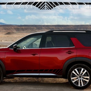 Puede incluir: Un SUV rojo con detalles en negro y ruedas negras y plateadas está estacionado en un paisaje desértico. El vehículo tiene techo y molduras negras. La imagen incluye un gráfico en la parte superior con el texto "CUSTOM GRAPHICS".