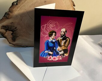 May include: A greeting card with a black frame and a white envelope. The card features a digital illustration of a couple sitting together against a pink background with a floral design. The woman is wearing a blue dress and the man is wearing a brown jacket.