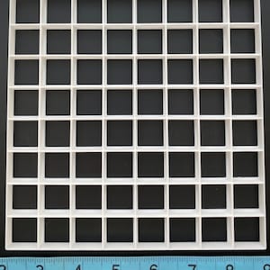 May include: White plastic grid with 49 square compartments. The grid is 17.8 cm wide and 17.8 cm long.