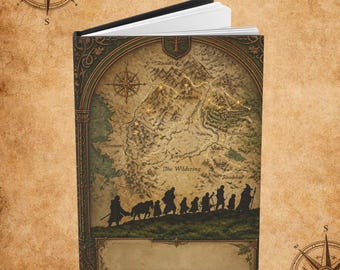 May include: A hardcover book featuring a fantasy map on the cover with a silhouette of a group of travelers walking across a landscape. The map includes text labels such as The Wildering and mountain ranges, with a compass rose in the corner.