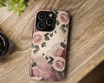 May include: A smartphone case featuring a soft, muted floral pattern with light pink and dusty rose roses, dark green leaves, and small white filler flowers against a creamy beige and pale pink background, with a black camera lens cutout.