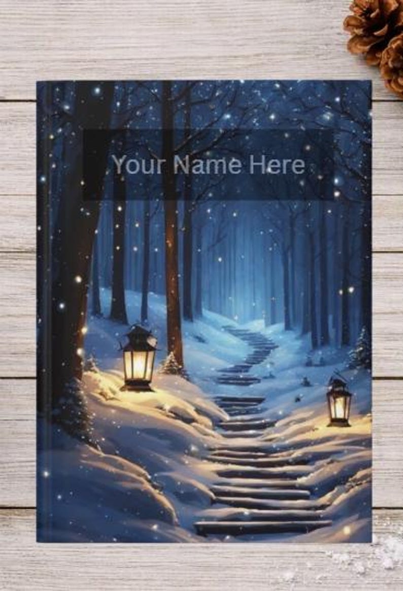 May include: A rectangular notebook with a cover featuring a snowy forest scene at night, illuminated by two glowing lanterns flanking a stone staircase. The text "Your Name Here" is printed in a dark rectangular box at the top center.