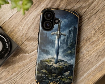 May include: A black smartphone case featuring a graphic illustration of a silver sword embedded in a stone block. The background depicts a dark, misty landscape with rocky terrain and ruins under a starry night sky, with gold accents.