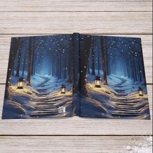 May include: A hardcover book featuring a wrap-around illustration of a snowy forest path at night. The scene depicts dark trees, a winding staircase covered in snow, and glowing lanterns emitting warm light against the cool blue winter atmosphere.