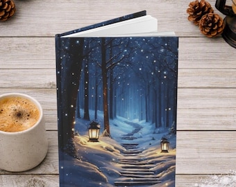 May include: A hardcover book featuring a winter forest scene on the cover, depicting a snow-covered path winding through dark trees, illuminated by two glowing lanterns, with white snow falling against a deep blue twilight sky background.