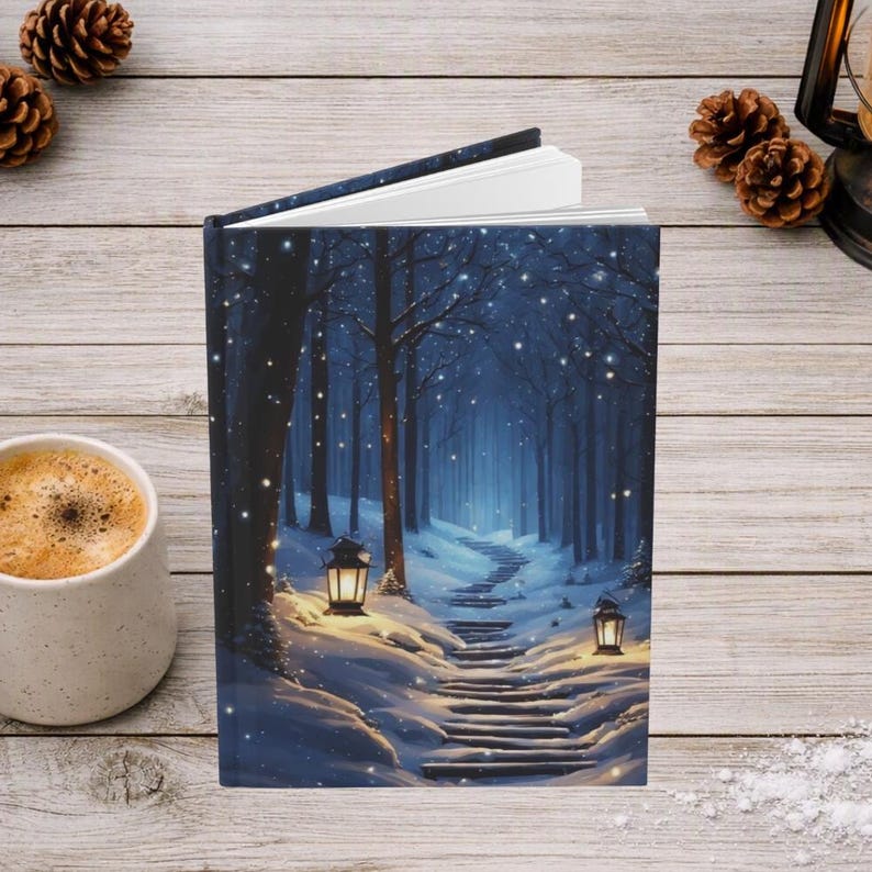 May include: A hardcover book featuring a winter forest scene on the cover, depicting a snow-covered path winding through dark trees, illuminated by two glowing lanterns, with white snow falling against a deep blue twilight sky background.