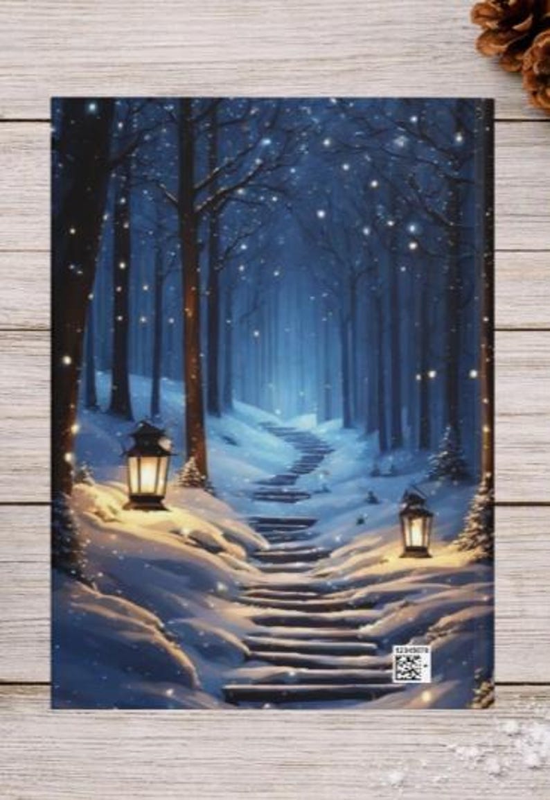 May include: A rectangular notebook cover featuring a winter forest scene at night with a snow-covered stone staircase leading into the trees. Two glowing lanterns illuminate the path, and small white lights are scattered throughout the dark blue forest.