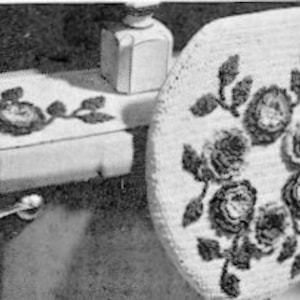 May include: A crocheted toilet seat cover and a matching crocheted tank cover with a floral design featuring roses and leaves.