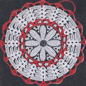 Pode incluir: Um crochê branco com uma borda vermelha. O crochê tem um design circular com uma flor no centro.