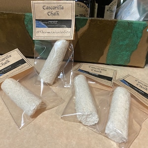 May include: Four white Cascarilla chalk sticks are individually packaged in clear plastic bags with brown paper labels that read "Cascarilla Chalk" and "Thorne's World".