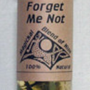 May include: A small glass bottle with a black cap, filled with a clear liquid and herbs. The bottle has a brown label with the words "Forget Me Not" and "Magical Blend of Oils". The label also includes a symbol and the words "100% Natural".