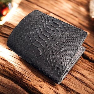 May include: A black bi-fold wallet with a textured, snake-skin pattern. The wallet is made of a dark material and is resting on a wooden surface. The wallet is closed and appears to be new.