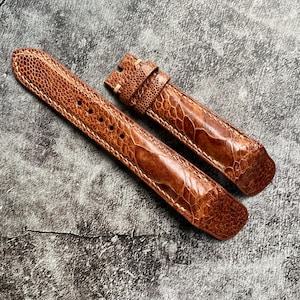 Puede incluir: Dos correas de reloj de cuero marrón con un patrón texturizado. Las correas están hechas de piel de avestruz.