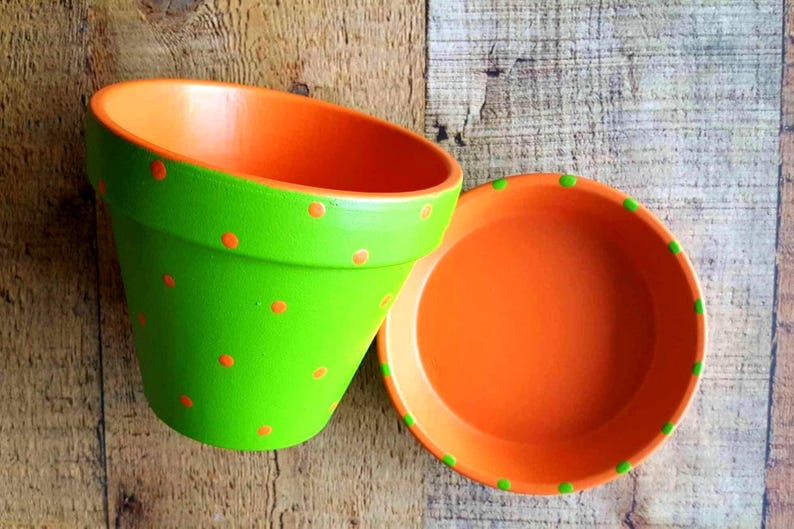 Medium painted polka dot planter in custom color combinations. Hand-painted terracotta flower pot with matching saucer, sealed for indoor or outdoor plants. Shown in orange and green.