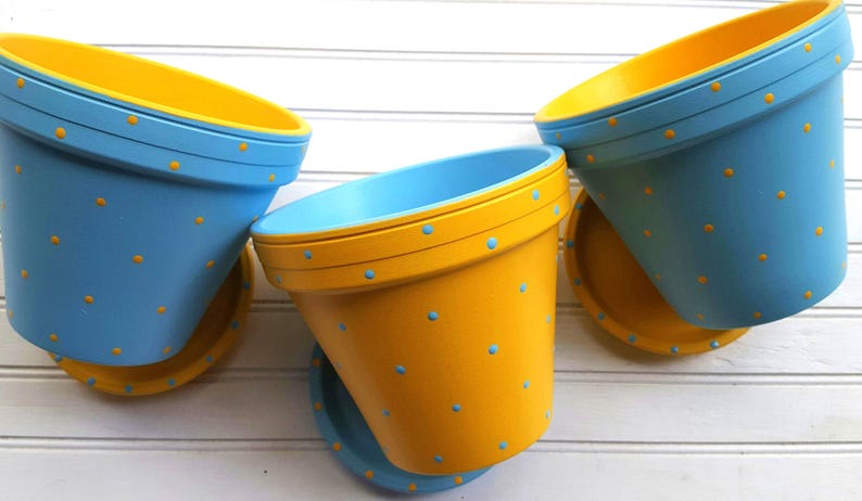 Medium painted polka dot planter in custom color combinations. Hand-painted terracotta flower pot with matching saucer, sealed for indoor or outdoor plants. Shown in yellow and blue with small dots.