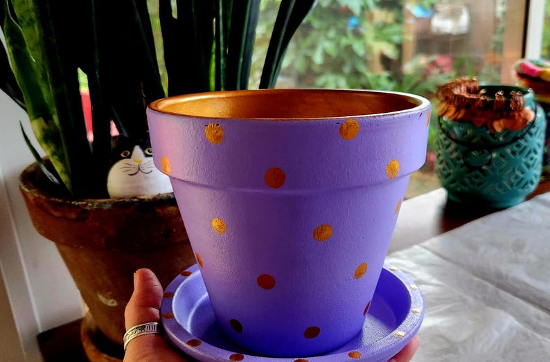 Medium painted polka dot planter in custom color combinations. Hand-painted terracotta flower pot with matching saucer, sealed for indoor or outdoor plants. Shown in purple and gold.