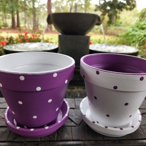 Medium painted polka dot planter in custom color combinations. Hand-painted terracotta flower pot with matching saucer, sealed for indoor or outdoor plants. Shown in purple and white.