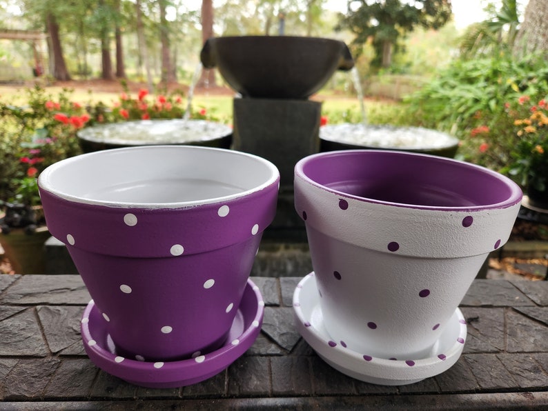 Medium painted polka dot planter in custom color combinations. Hand-painted terracotta flower pot with matching saucer, sealed for indoor or outdoor plants. Shown in purple and white.