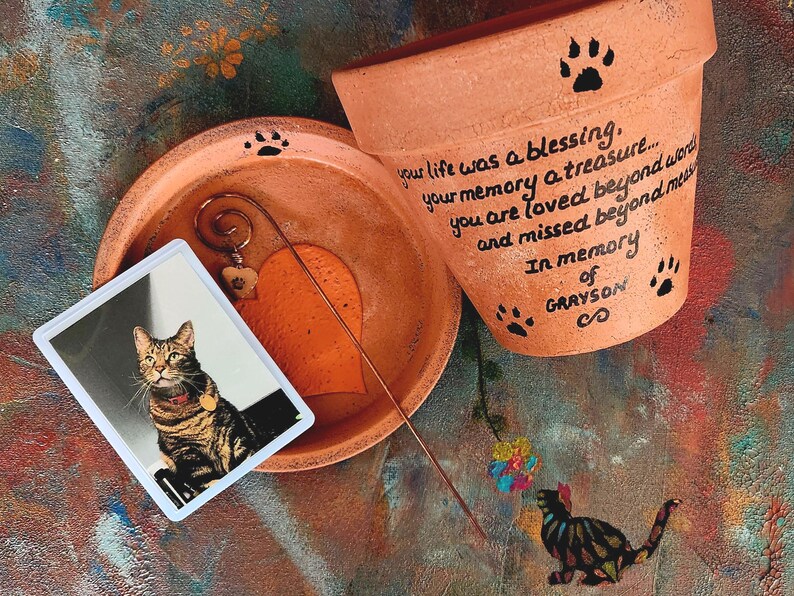 Personalized pet memorial planter with custom name and message.
Hand painted terracotta pet loss planter with matching saucer shown in orange.