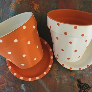 Medium painted polka dot planter in custom color combinations. Hand-painted terracotta flower pot with matching saucer, sealed for indoor or outdoor plants. Shown in orange and white.