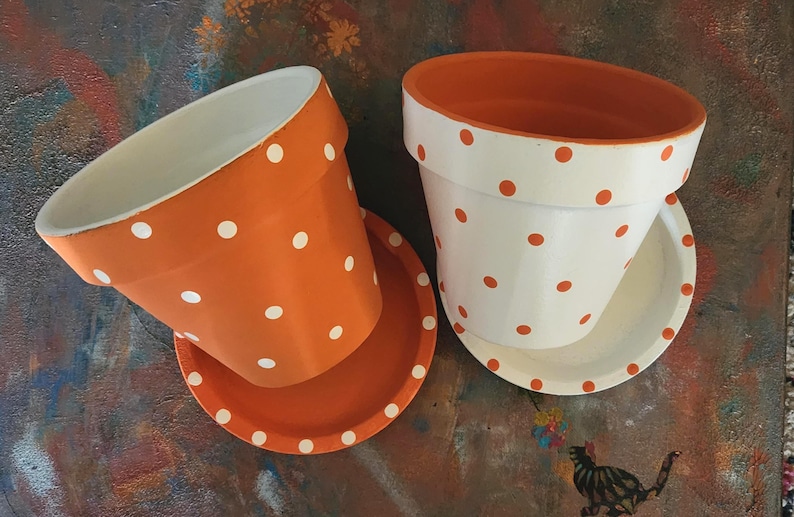 Medium painted polka dot planter in custom color combinations. Hand-painted terracotta flower pot with matching saucer, sealed for indoor or outdoor plants. Shown in orange and white.