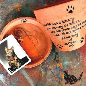 Hand-painted personalized pet memorial planter with custom wording and colors. Terracotta sympathy pot with pet name for dog or cat loss, Rainbow Bridge tribute.  Shown in orange.