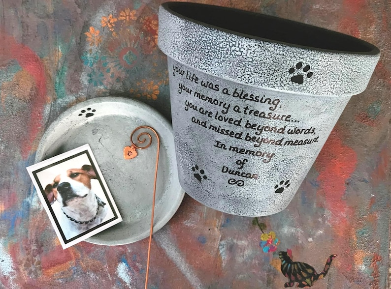 Personalized pet memorial planter with custom name and message.
Hand painted terracotta pet loss planter with matching saucer shown in gray.