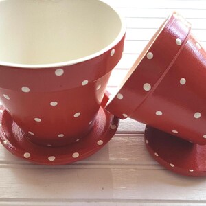 Medium painted polka dot planter in custom color combinations. Hand-painted terracotta flower pot with matching saucer, sealed for indoor or outdoor plants. Shown in red and white.