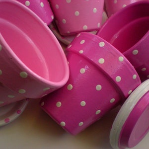 Medium painted polka dot planter in custom color combinations. Hand-painted terracotta flower pot with matching saucer, sealed for indoor or outdoor plants. Shown in hot pink and white.