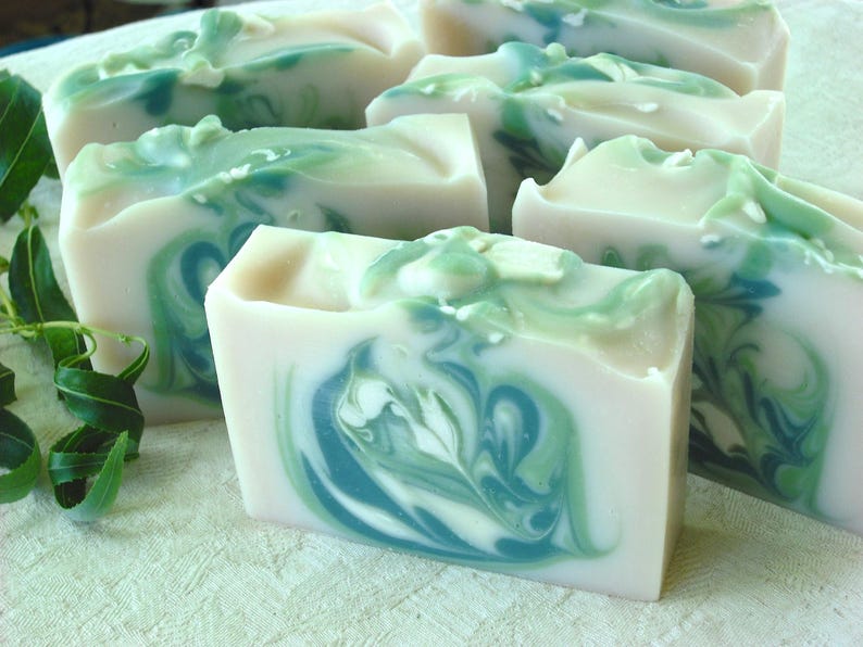 May include: A collection of handmade soap bars with a swirling green and white pattern. The soap bars are arranged on a white surface.