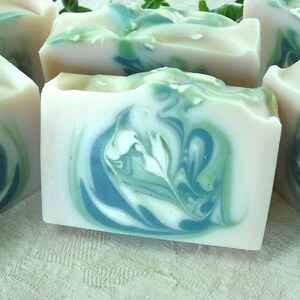 May include: Four bars of handmade soap with a swirling green and white pattern. The soap is made with natural ingredients and is perfect for sensitive skin.