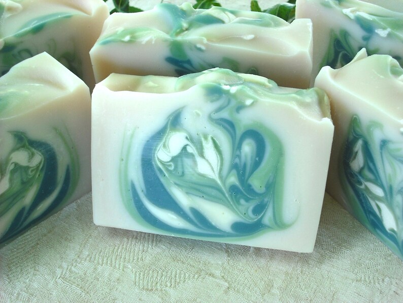 May include: Four bars of handmade soap with a swirling green and white pattern. The soap is made with natural ingredients and is perfect for sensitive skin.
